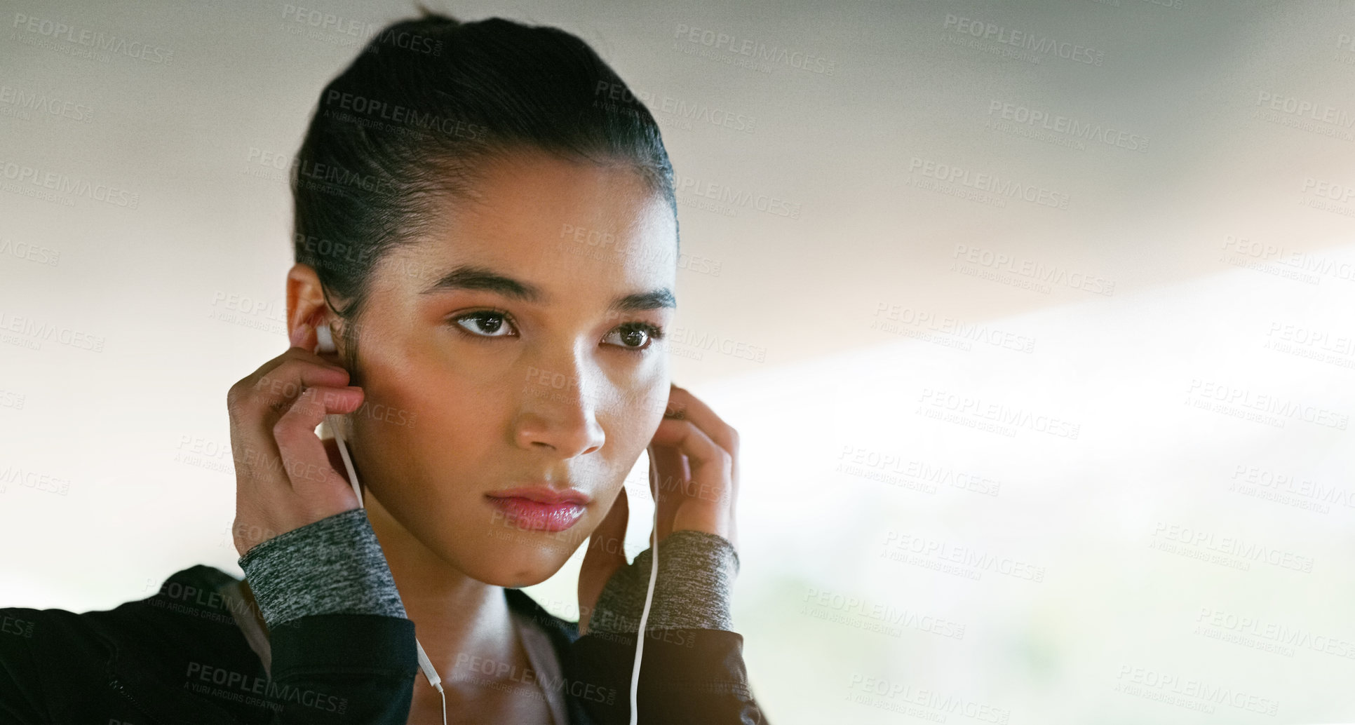 Buy stock photo Cropped shot of an attractive young woman listening to music while working out outdoors