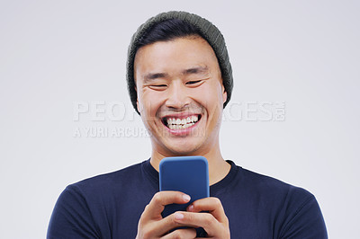 Buy stock photo Phone, laugh and Asian man online in studio with smile for social media, internet humor and funny chat. Communication, gray background and male person on smartphone for website, mobile app and meme