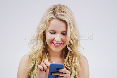 Buy stock photo Smile, social media and woman with a smartphone, typing and communication against a grey studio background. Female person, girl and model with a cellphone, network and online reading with happiness