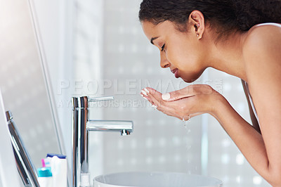 Buy stock photo Cropped shot of a young woman washing her face in the bathroom at home
