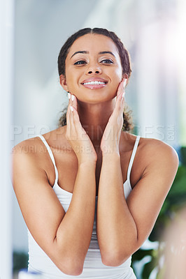 Buy stock photo Cropped shot of an attractive young woman touching her face during her morning routine