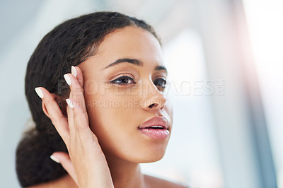 Buy stock photo Cropped shot of an attractive young woman touching her face during her morning routine