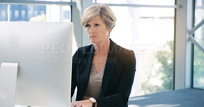 Buy stock photo Computer, concentration and mature business woman at desk in office for online report or task. Desktop, reading and typing with serious employee in corporate workplace for professional management
