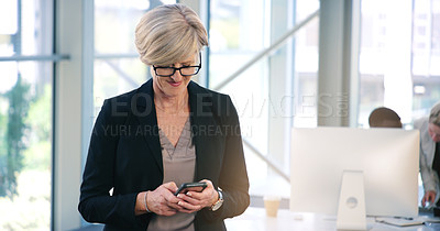 Buy stock photo Shot of a mature businesswoman texting on a cellphone in an office