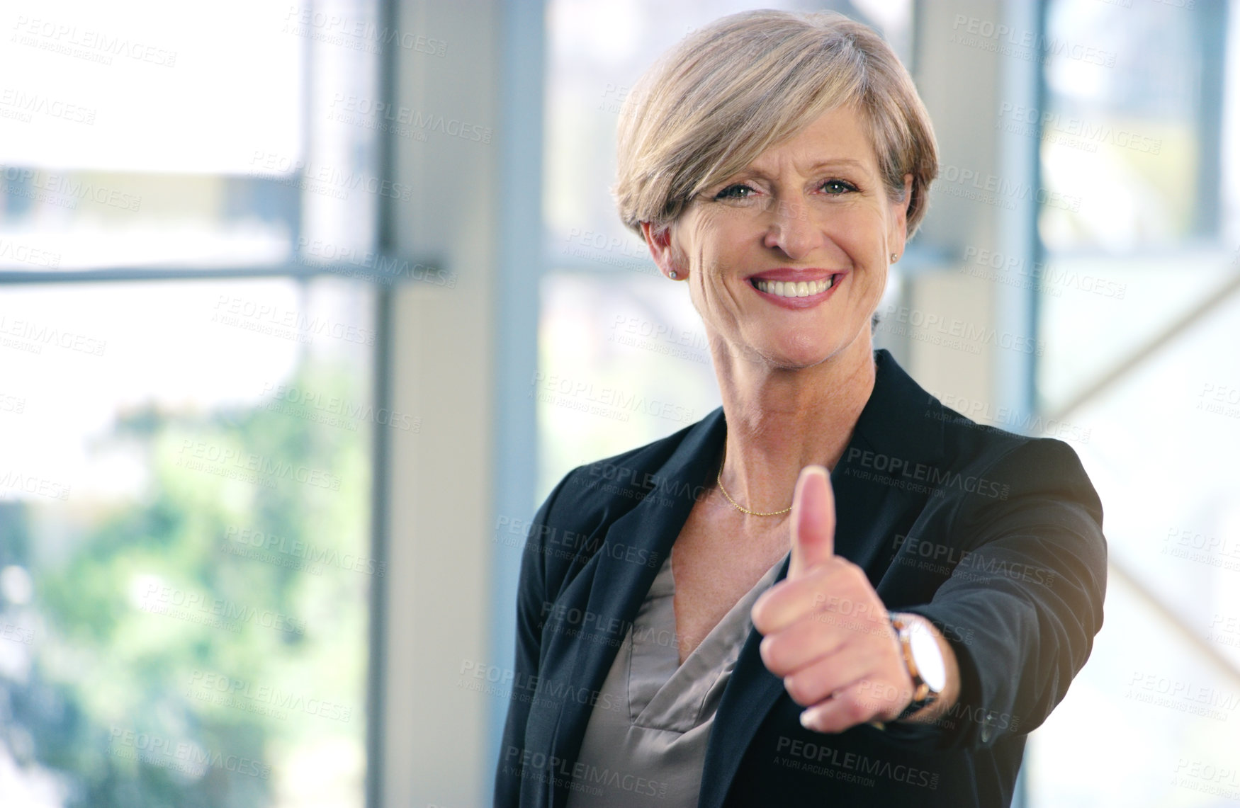 Buy stock photo Portrait of a mature businesswoman showing thumbs up in an office