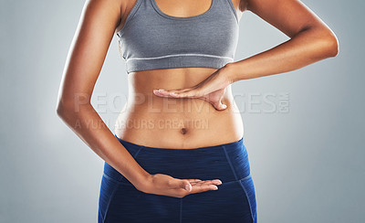 Buy stock photo Cropped studio shot of an unrecognizable young woman framing her stomach against a gray background