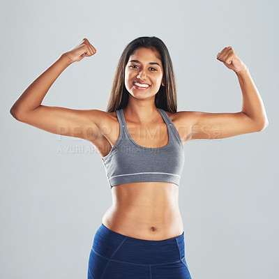 Buy stock photo Cropped studio portrait of an attractive young woman flexing her biceps against a gray background