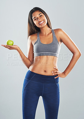 Buy stock photo Cropped studio portrait of an attractive young woman holding an apple against a gray background