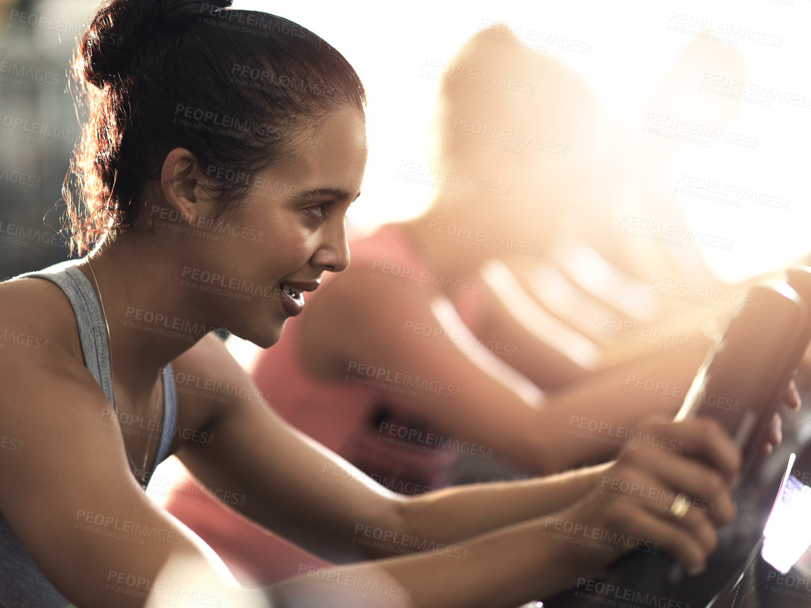 Buy stock photo Shot of a group of young people working out on elliptical machines in the gym