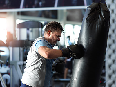Buy stock photo Shot of a mature man working out on a punching bag in the gym