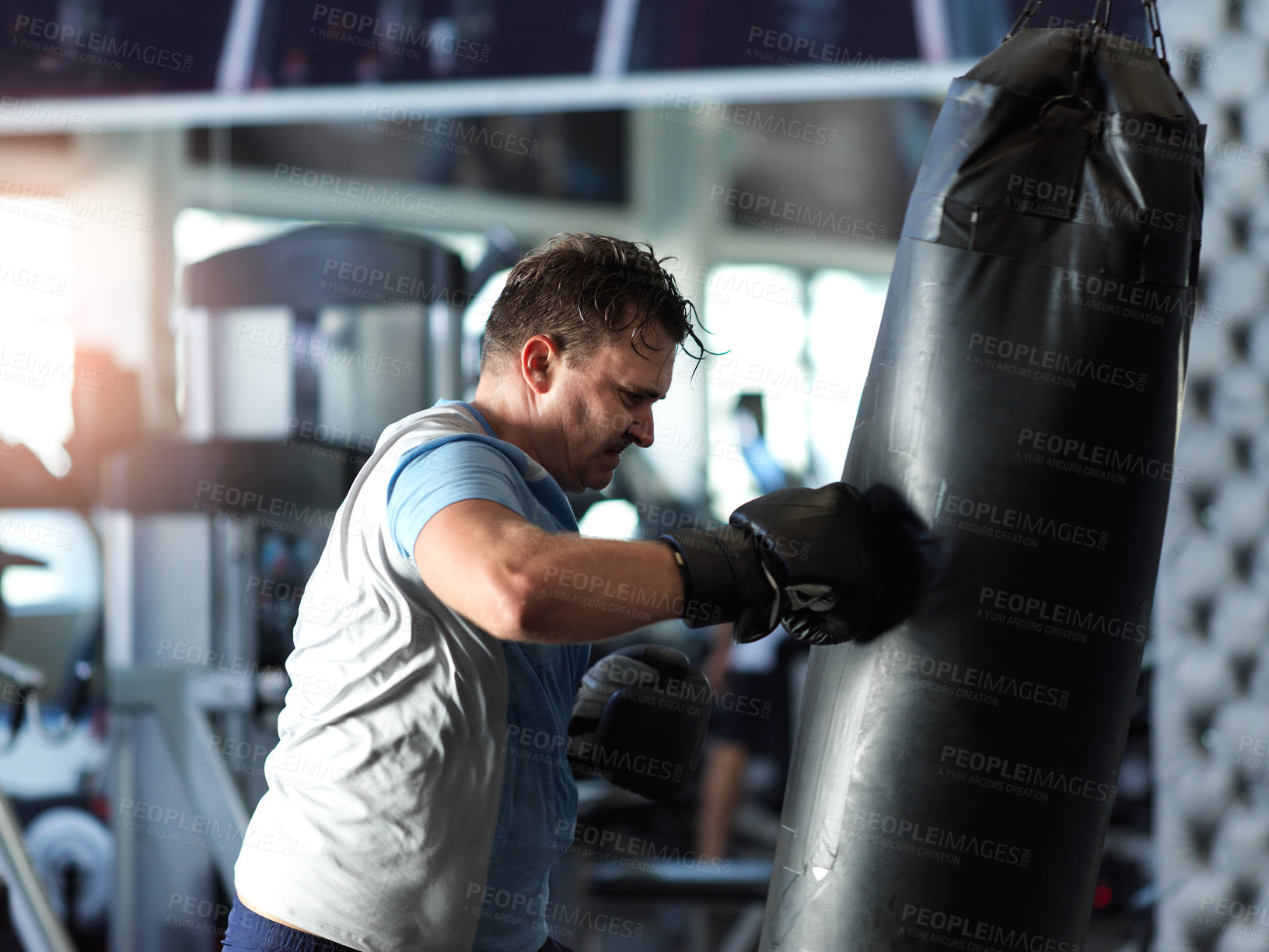 Buy stock photo Shot of a mature man working out on a punching bag in the gym