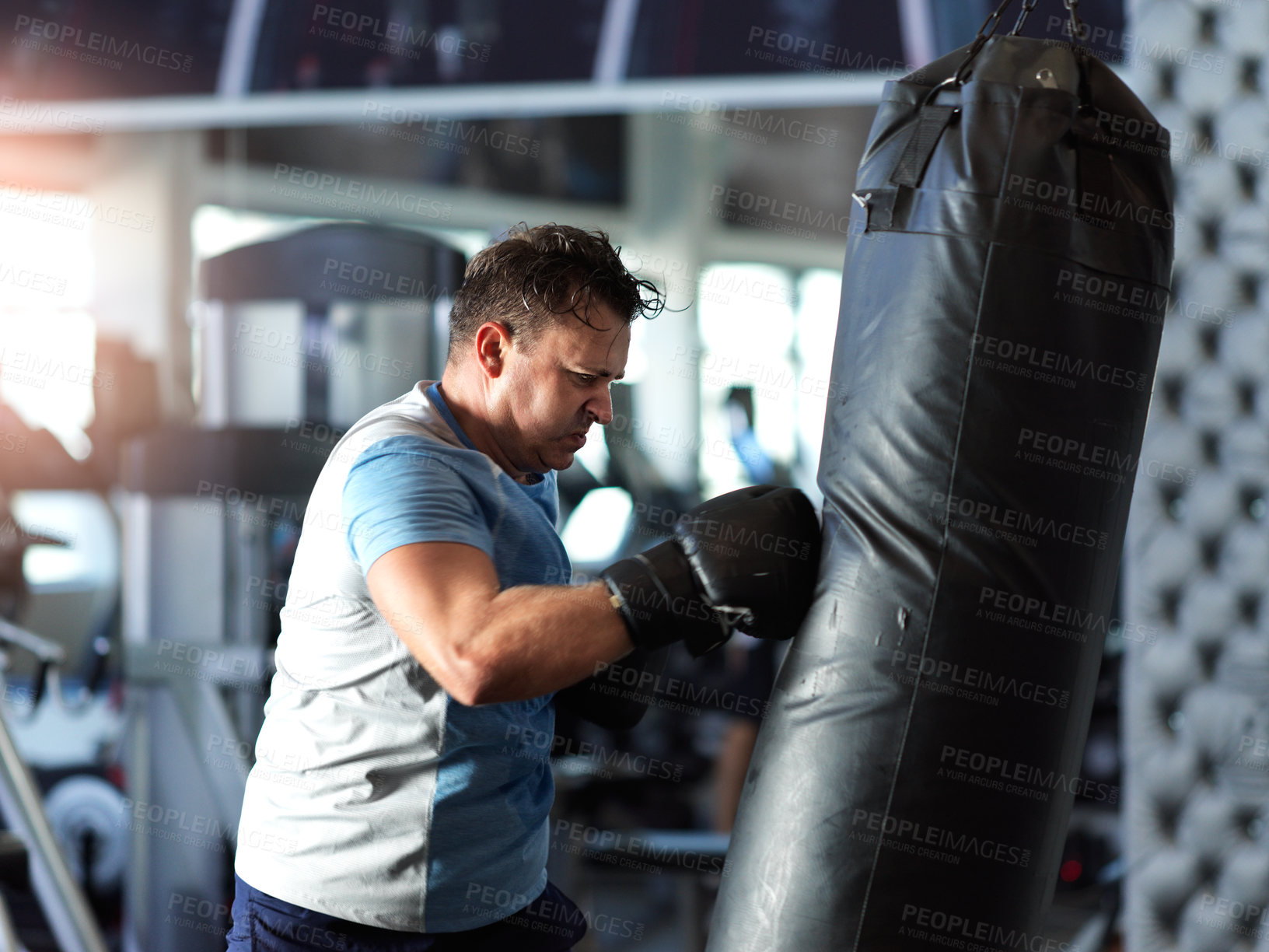 Buy stock photo Shot of a mature man working out on a punching bag in the gym