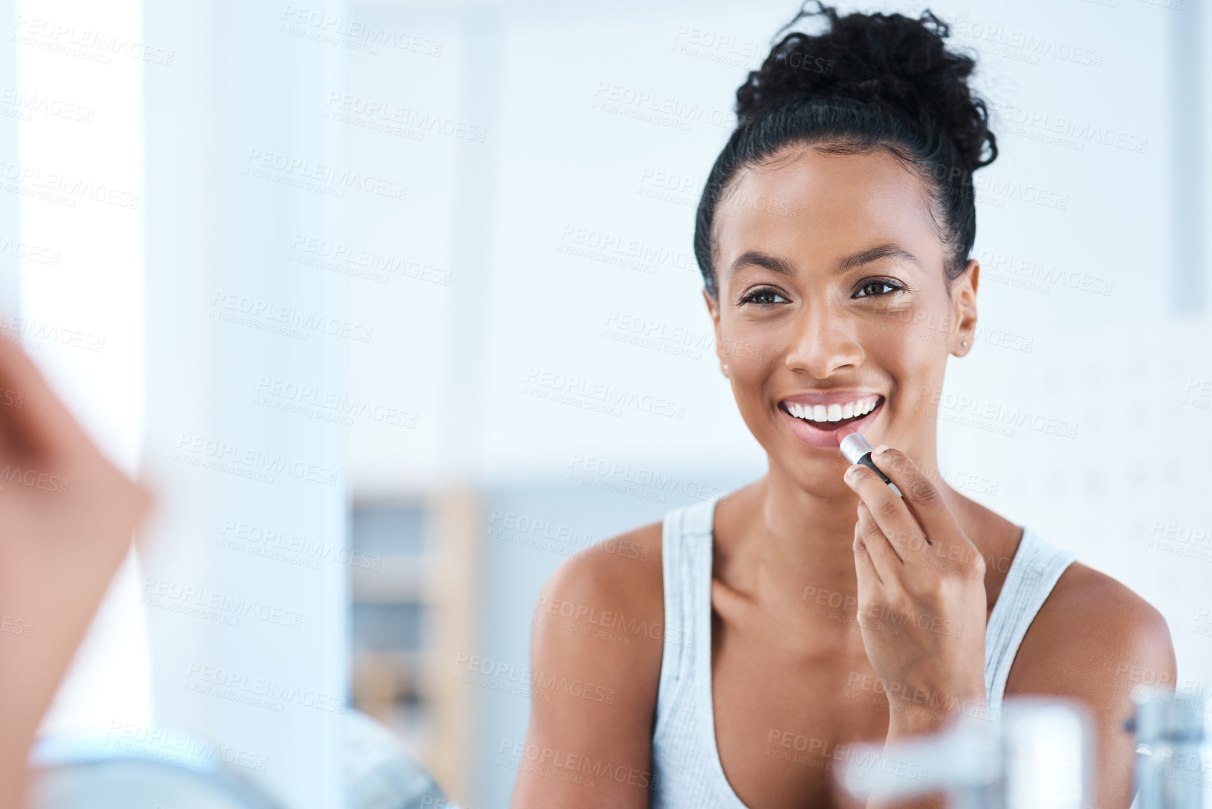 Buy stock photo Shot of a young woman applying lipstick in her bathroom mirror