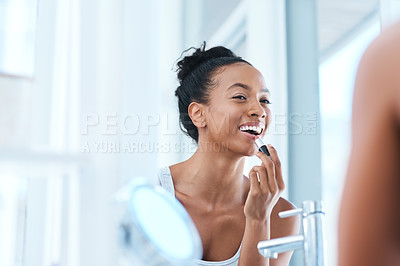 Buy stock photo Shot of a young woman applying lipstick in her bathroom mirror