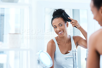 Buy stock photo Cropped shot of a beautiful young woman brushing her hair in the bathroom at home