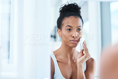 Buy stock photo Portrait of an attractive young woman cleaning her face with a cotton pad in the bathroom at home