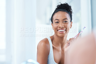 Buy stock photo Cropped shot of an attractive young woman brushing her teeth in the bathroom at home