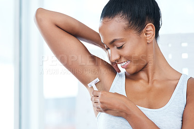 Buy stock photo Shot of an attractive young woman shaving her under arms with a razor in the bathroom