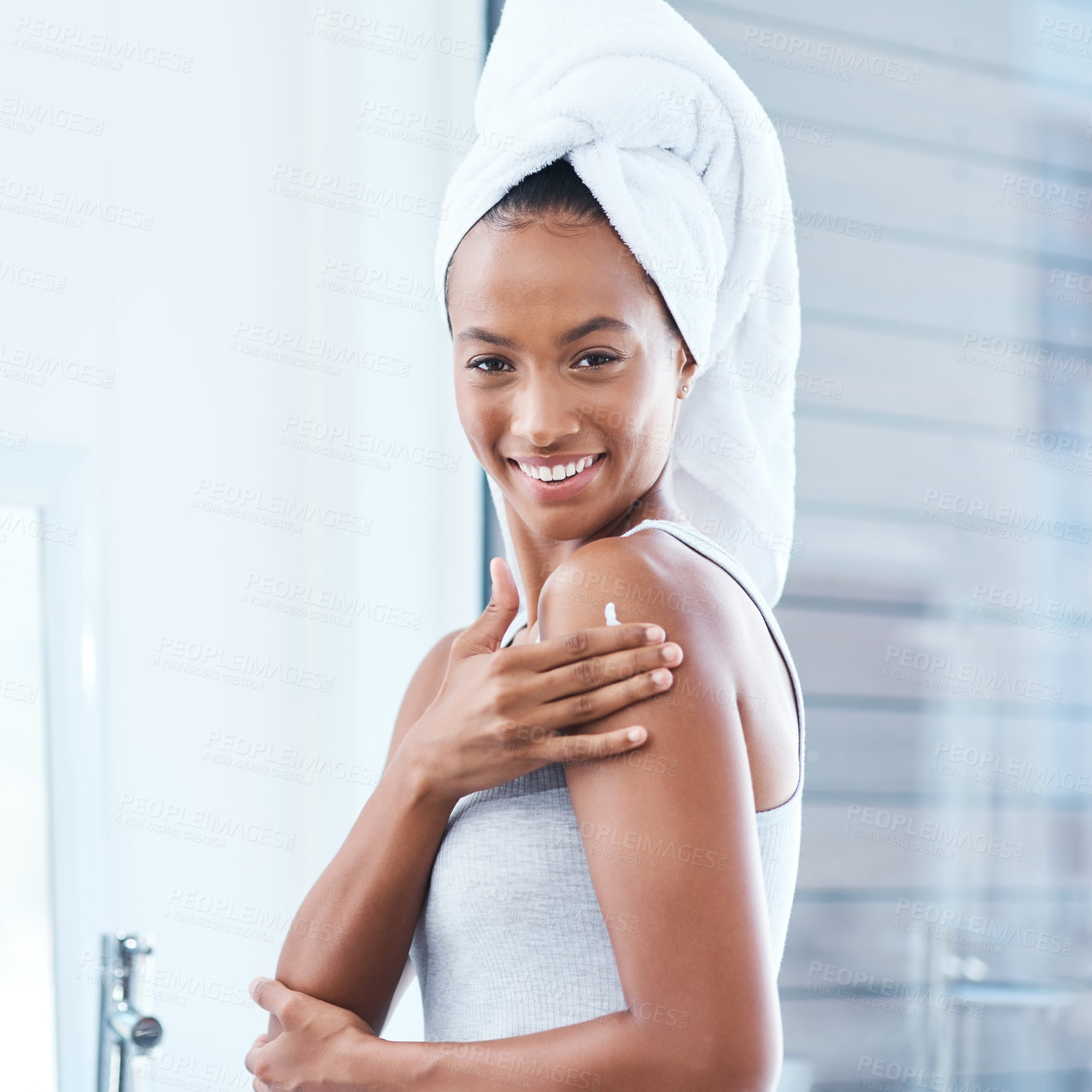 Buy stock photo Shot of a young woman applying moisturizer to her body