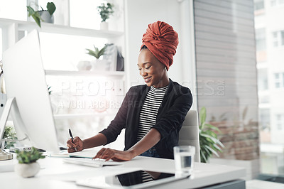 Buy stock photo Cropped shot of an attractive young businesswoman taking notes while working at her desk in the office