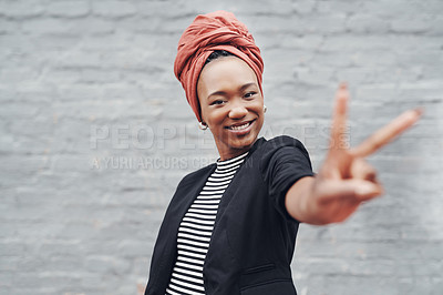 Buy stock photo Cropped portrait of an attractive young businesswoman giving you the peace sign against a grey brick wall outside