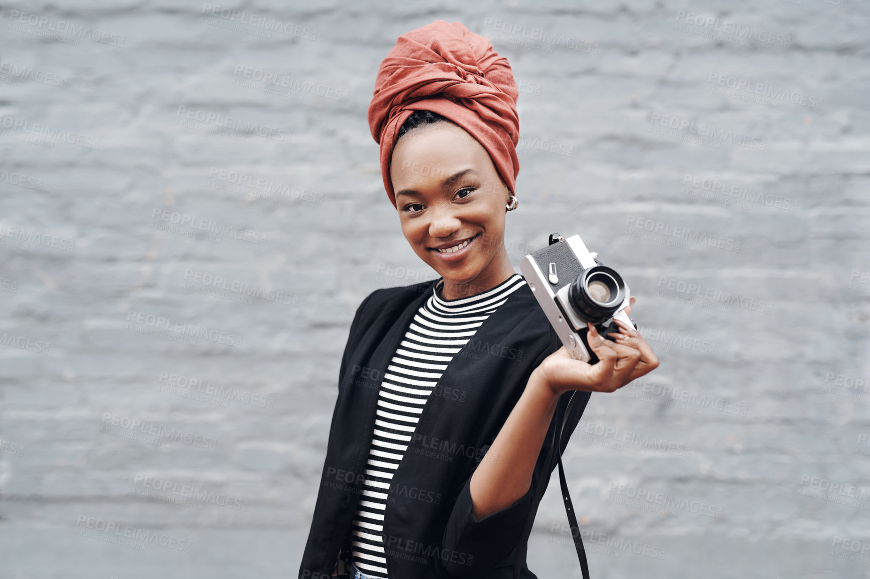 Buy stock photo Cropped portrait of an attractive young businesswoman posing with her camera against a grey brick wall outside