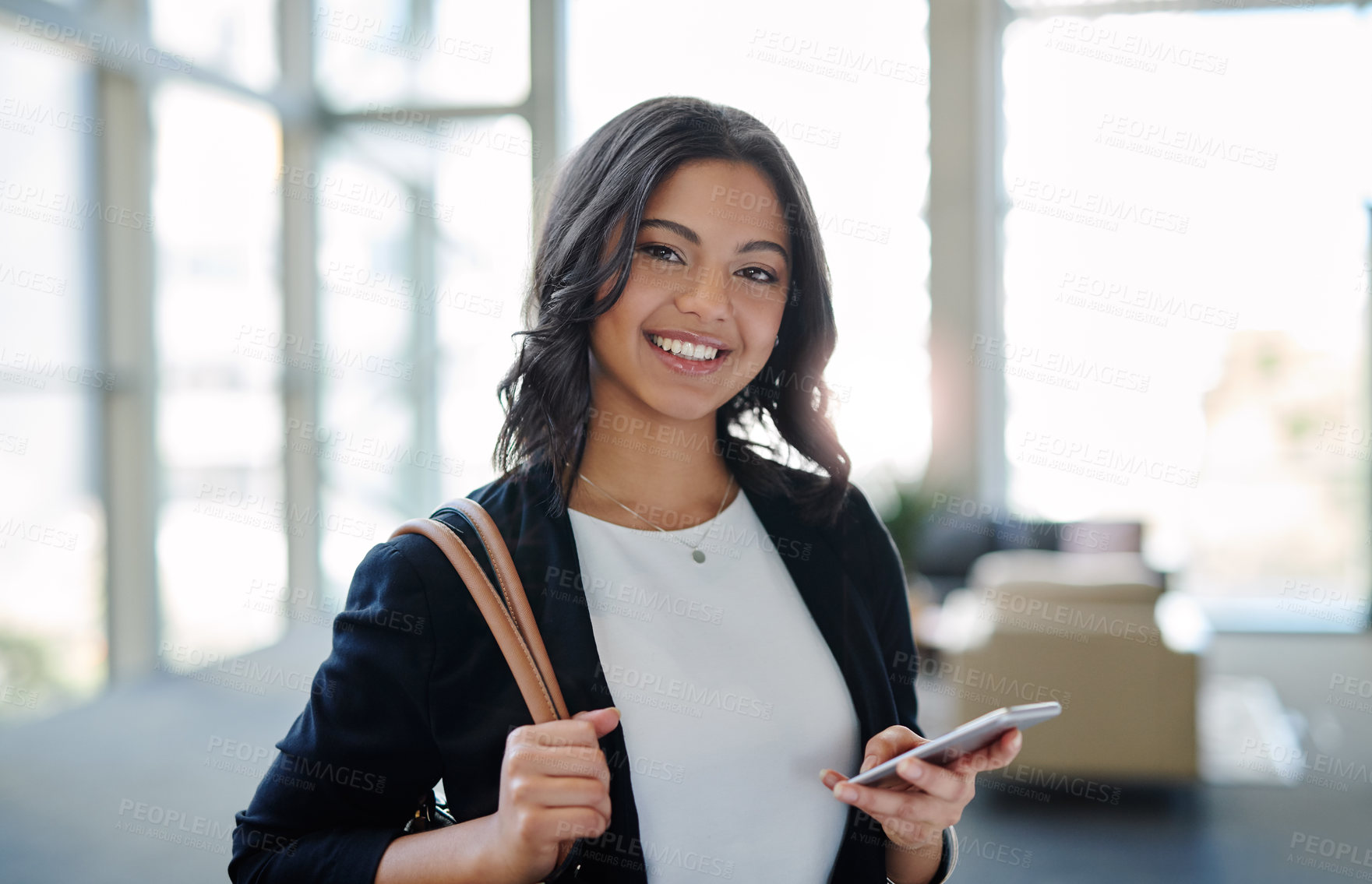 Buy stock photo Cropped portrait of an attractive young businesswoman smiling while using a smartphone in a modern office