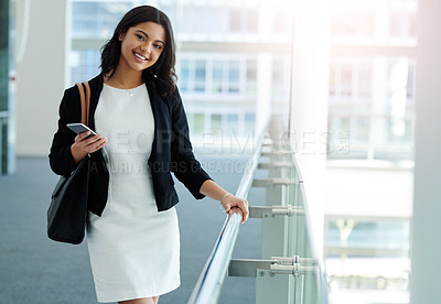Buy stock photo Cropped portrait of an attractive young businesswoman smiling while holding a smartphone in a modern office