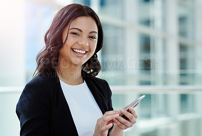 Buy stock photo Cropped portrait of an attractive young businesswoman smiling while using a smartphone in a modern office