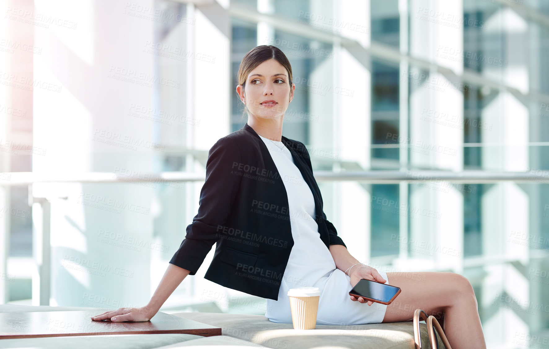 Buy stock photo Cropped shot of an attractive young businesswoman looking thoughtful while using a smartphone in a modern office