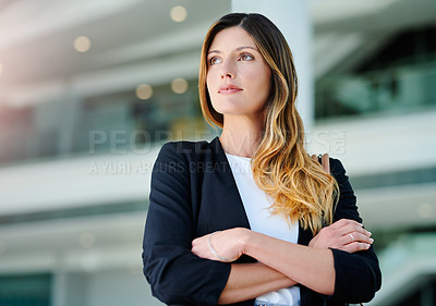Buy stock photo Cropped shot of an attractive young businesswoman looking thoughtful while standing with her arms crossed in a modern office