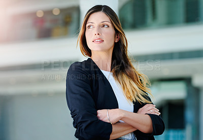 Buy stock photo Cropped shot of an attractive young businesswoman looking thoughtful while standing with her arms crossed in a modern office