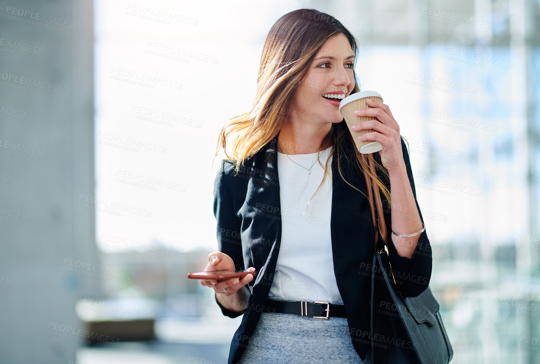 Buy stock photo Cropped shot of an attractive young businesswoman drinking coffee while walking through a modern office
