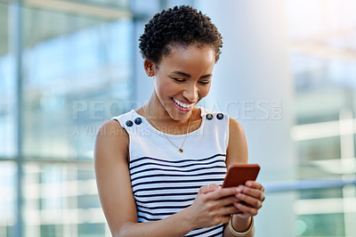 Buy stock photo Cropped shot of an attractive young businesswoman smiling using a smartphone in a modern workplace