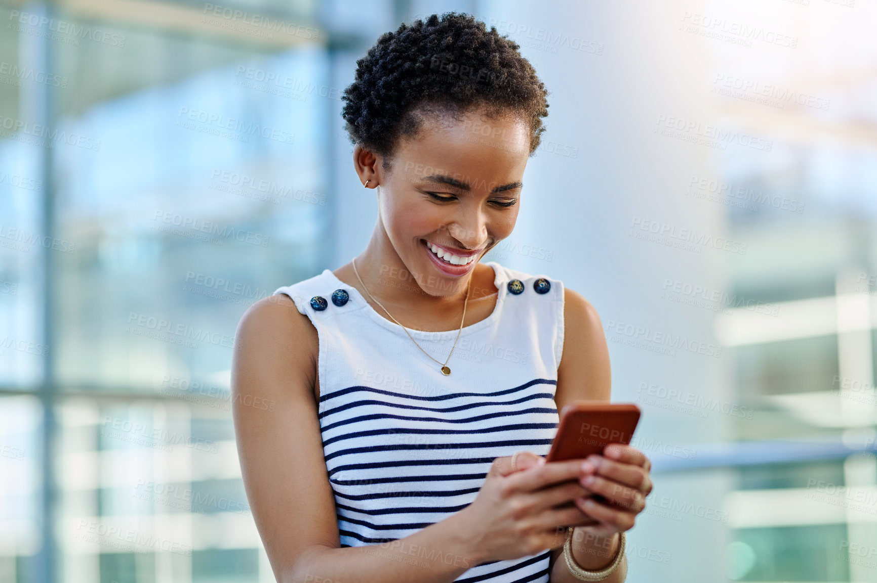 Buy stock photo Cropped shot of an attractive young businesswoman smiling using a smartphone in a modern workplace