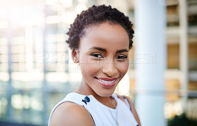 Buy stock photo Cropped portrait of an attractive young businesswoman smiling while standing in a modern workplace