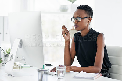 Buy stock photo Shot of a confident young businesswoman using a computer in a modern office