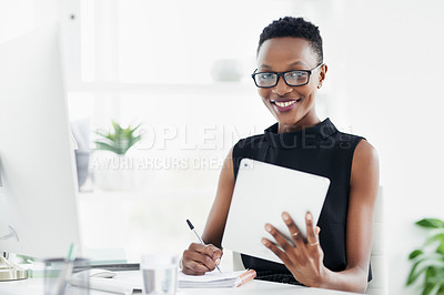 Buy stock photo Shot of a confident young businesswoman writing in a notebook and using a digital tablet in a modern office