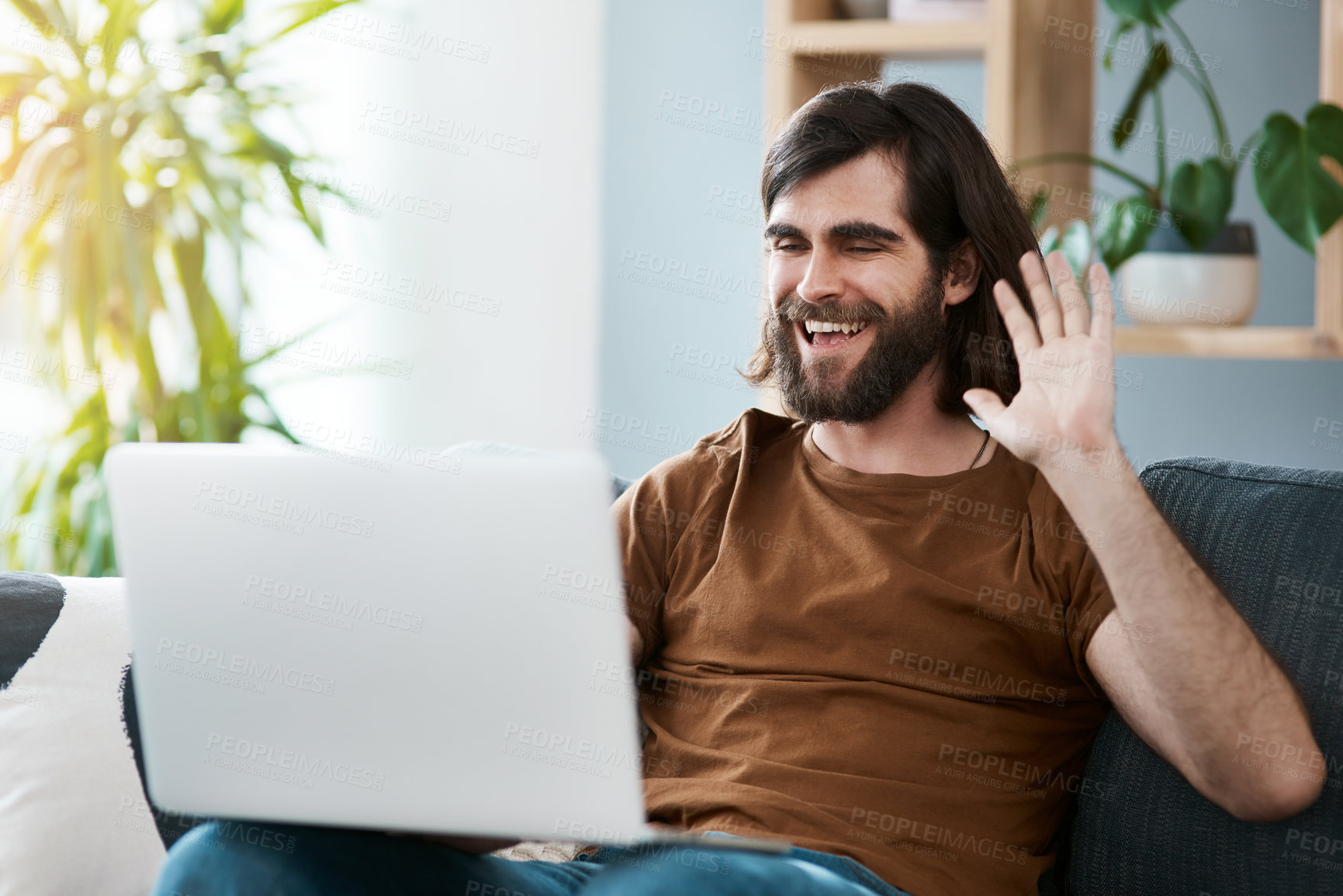 Buy stock photo Shot of a handsome young man using his laptop while relaxing on a sofa in his living room