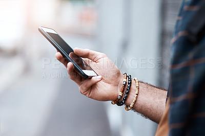 Buy stock photo Shot of an unrecognizable man using his cellphone in the city