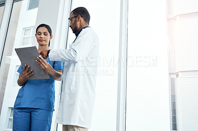 Buy stock photo Shot of two young doctors using a digital tablet in a modern hospital