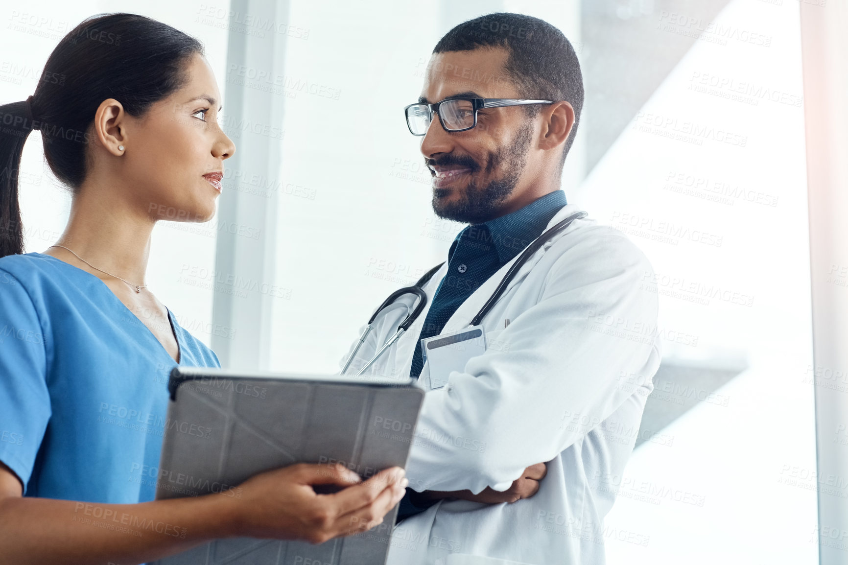 Buy stock photo Shot of two young doctors using a digital tablet in a modern hospital