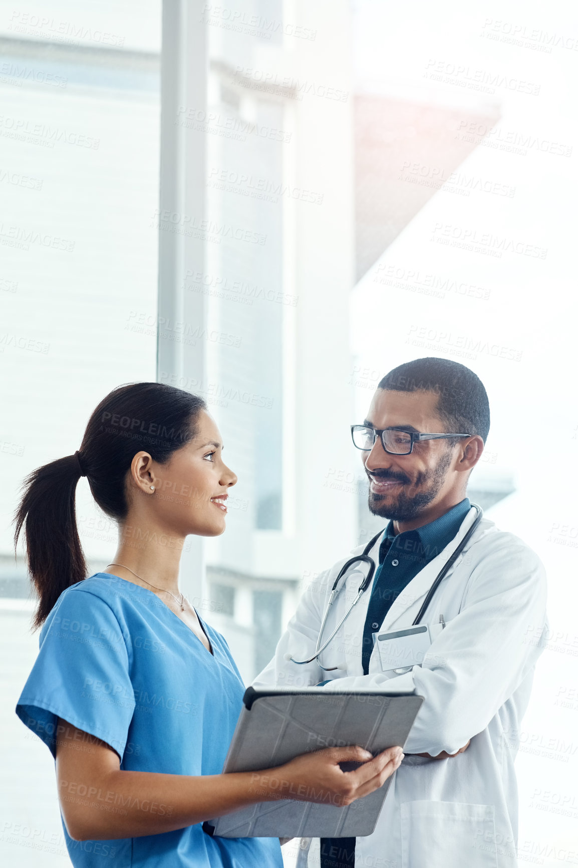 Buy stock photo Shot of two young doctors using a digital tablet in a modern hospital