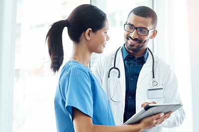 Buy stock photo Shot of two young doctors using a digital tablet in a modern hospital