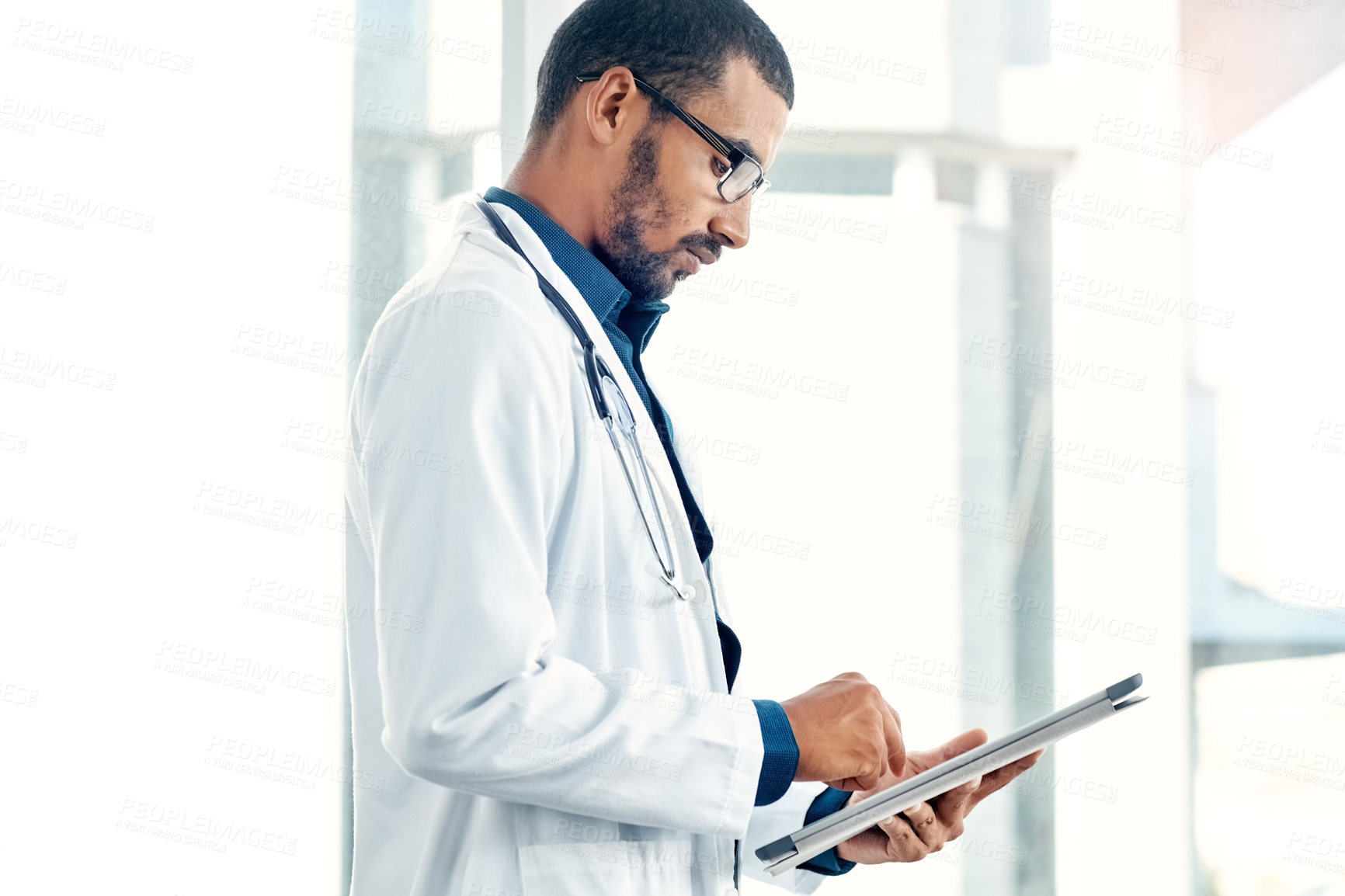 Buy stock photo Shot of a young doctor using a digital tablet in a modern hospital