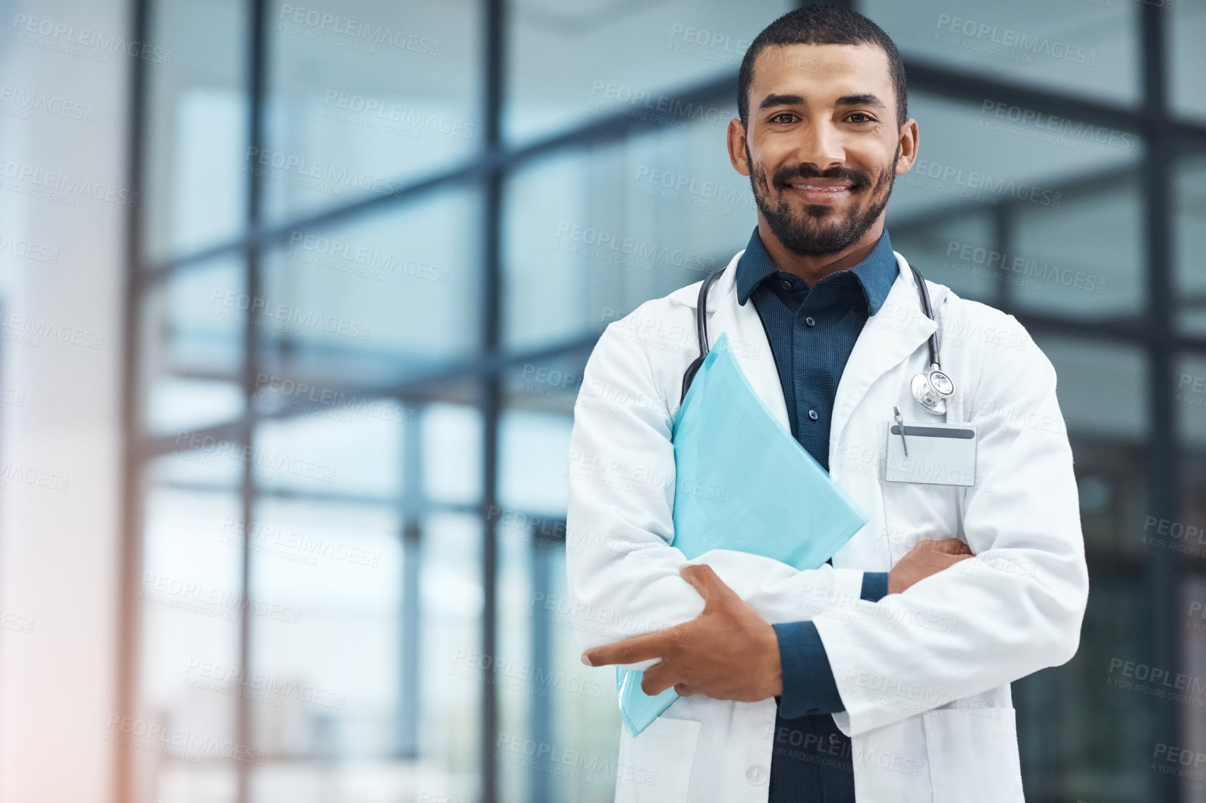 Buy stock photo Portrait of a young doctor holding a file in a modern hospital
