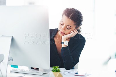 Buy stock photo Shot of a young businesswoman looking bored while working on a computer in an office