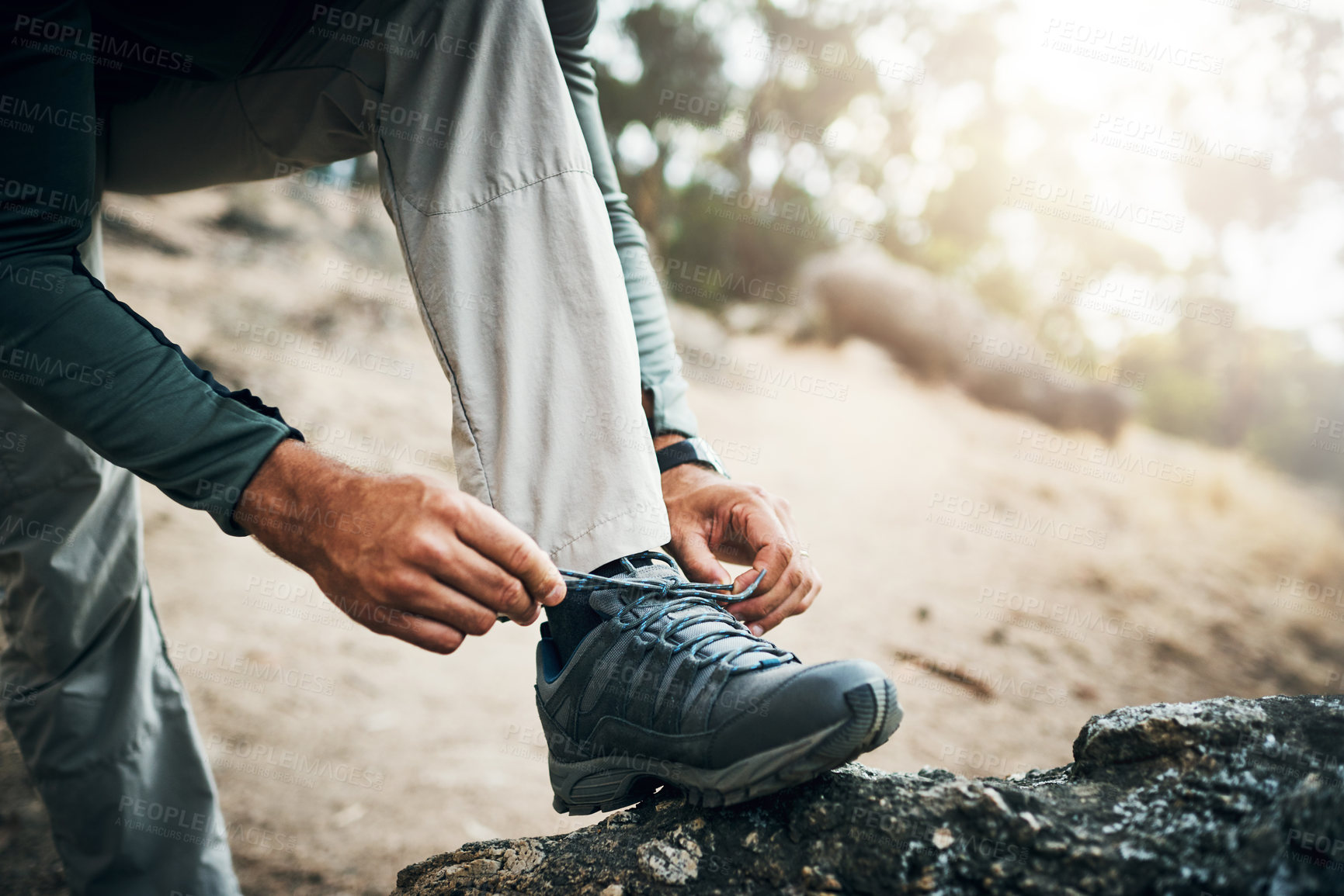 Buy stock photo Cropped shot of a unrecognizable man tying his shoe laces before going for a hike up a mountain