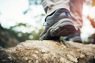 Buy stock photo Low angle shot of an unrecognizable man walking on rocks up a mountain outside during the day