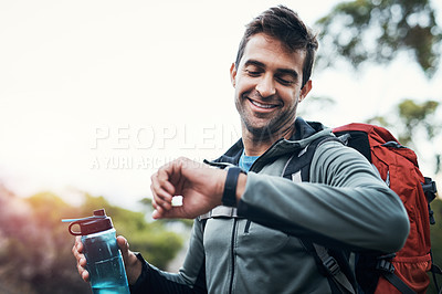 Buy stock photo Cropped shot of a cheerful young man looking at his watch while going for a hike up a mountain